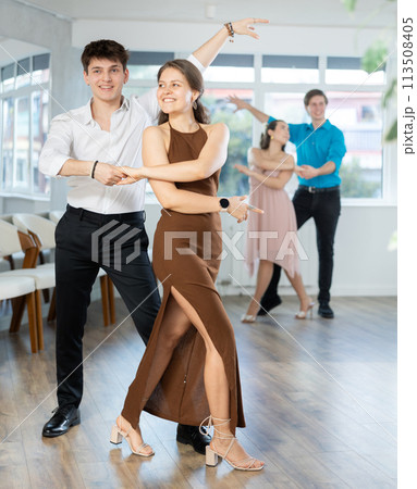 Couple in evening dresses enjoys pair dance tango, interacting with each other on floor Couple in evening dresses enjoys pair dance tango, interacting with each other on floor 113508405