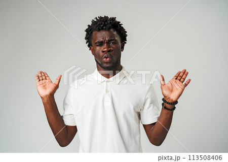 Young Man Expressing Confusion and Surprise With Hands Up Against a Neutral Background 113508406