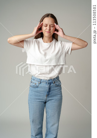 Young woman suffering headache on gray background Young woman suffering headache on gray background 113508581