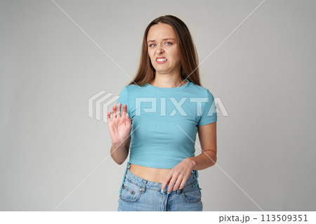 Young beautiful woman over gray background with disgusted displeased expression on gray background 113509351