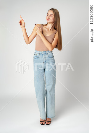 Young Woman in Tank Top Pointing at Something on gray background 113509590