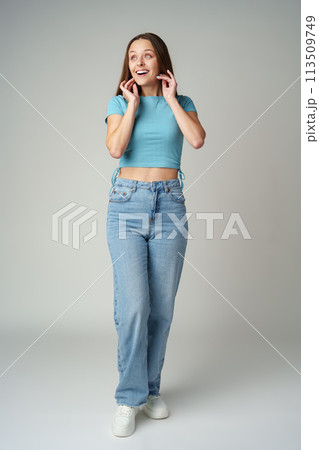 Young woman in blue T-shirt posing to camera on gray background 113509749