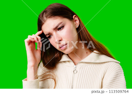 Young Woman Contemplating Deeply Against a Vibrant Green Background 113509764