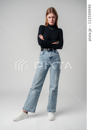 Young Woman Wearing Black Top and Jeans against gray background Young Woman Wearing Black Top and Jeans against gray background 113509940