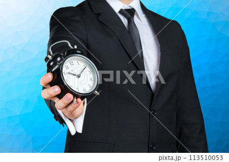 Unrecognizable businessman with an alarm clock in a hand Unrecognizable businessman with an alarm clock in a hand 113510053