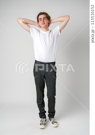 Young Man in White T-Shirt and Black Pants Standing Relaxed With Hands Behind Head Young Man in White T-Shirt and Black Pants Standing Relaxed With Hands Behind Head 113510152