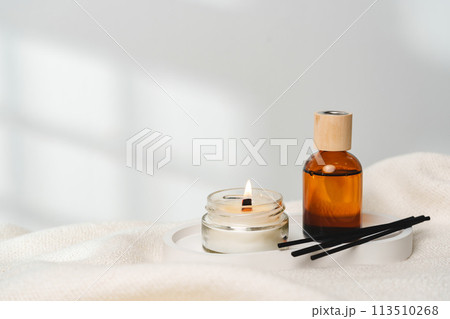 Elegant Aroma Diffuser With Reed Sticks And Scented Candle On White Tablecloth Elegant Aroma Diffuser With Reed Sticks And Scented Candle On White Tablecloth 113510268