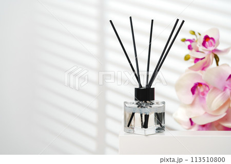 Elegant Reed Diffusers Beside Blooming Orchids in a Bright Interior Setting 113510800