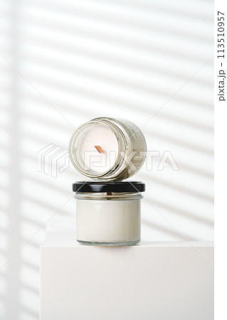 Candle With Extinguished Flame Resting on Glass Jar Near Blinds 113510957