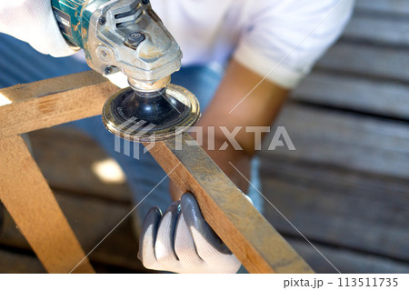 A person works with a power tool, sending sawdust flying as they  shape a piece of wood. A person works with a power tool, sending sawdust flying as they  shape a piece of wood. 113511735