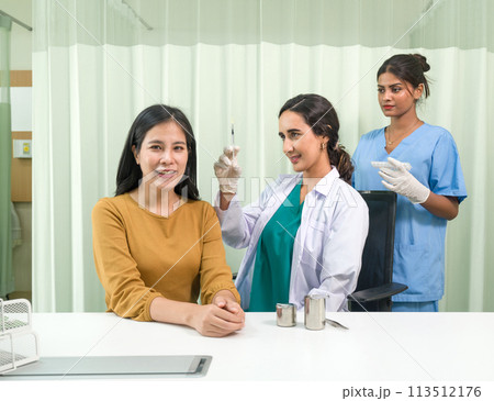 Doctor in white gown and protective glove prepare to give an injection to a female patient. Doctor in white gown and protective glove prepare to give an injection to a female patient. 113512176