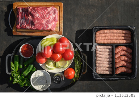 Fresh fish, beef meat, vegetables and sausages for preparation barbecue grill on black table outside. View from above. BBQ. Festive summer party. Outdoors. 113512305
