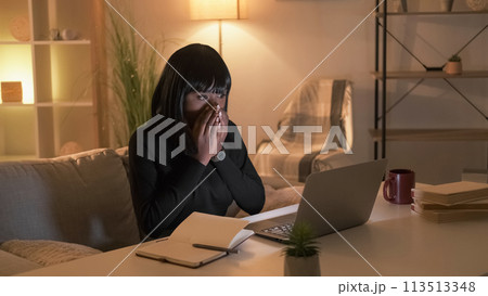 Shocked news. Excited woman. Online connection. Happy female student looking laptop covering mouth with hands in evening room interior. 113513348