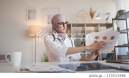 Medical charts. Health insurance. Serious woman doctor discussing analysis report statistics graphs at webinar video call meeting at hospital. Medical charts. Health insurance. Serious woman doctor discussing analysis report statistics graphs at webinar video call meeting at hospital. 113513446