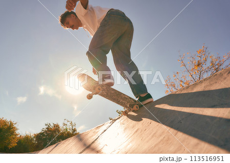 A young man doing tricks on his skateboard at the skate park. Active sport concept A young man doing tricks on his skateboard at the skate park. Active sport concept 113516951