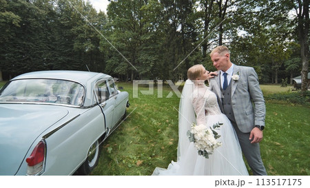 Bride and groom posing in front of white car for wedding picture Bride and groom posing in front of white car for wedding picture 113517175