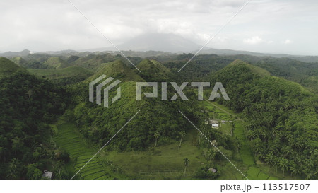 Asia countryside aerial: green hill view at volcano smoke haze horizon. Rural Philippine landscape Asia countryside aerial: green hill view at volcano smoke haze horizon. Rural Philippine landscape 113517507