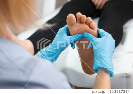 Close up of masseur doing foot reflexology massage to woman at beauty salon. 113517814