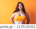 A woman wearing an orange top strikes a simple yet striking pose for a picture. 113518162