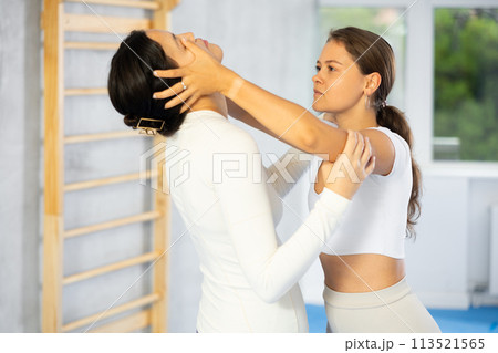 Woman and trainer train painful hold on self-defense course in boxing gym Woman and trainer train painful hold on self-defense course in boxing gym 113521565