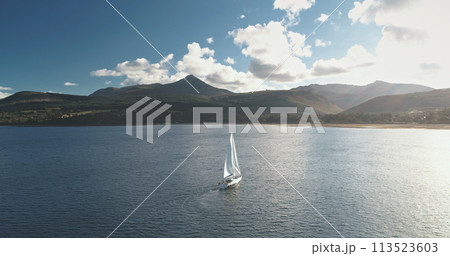 Slow motion of sailing yacht at mountain ocean coast. Sailboat regatta race at sea bay aerial 113523603