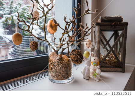 Charming Easter themed luxury hotel display in Zermatt, Swiss ski resort. Glass vase with branches, pastel eggs, rustic lantern, bunny figurines, snowy backdrop. Charming Easter themed luxury hotel display in Zermatt, Swiss ski resort. Glass vase with branches, pastel eggs, rustic lantern, bunny figurines, snowy backdrop. 113525515