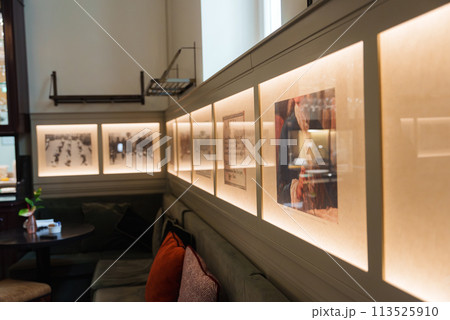 Luxury hotel interior in Rome featuring well lit wall with framed artworks, plush green sofa with red cushions, creating a sophisticated and inviting ambiance. 113525910