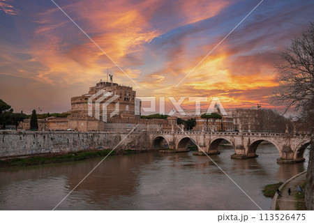 A scenic view of Castel Sant'Angelo and Ponte Sant'Angelo bridge over Tiber River in Rome, Italy. Historical landmarks, river, and cloudy sky with hints of blue. 113526475