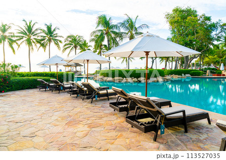 Umbrella and chair around swimming pool in resort hotel for leisure travel and vacation neary sea ocean beach 113527035