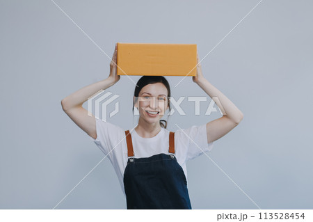 Smiling Asian woman in casual clothes holding a cardboard box mockup while standing against an isolated white background. shipping business concept Smiling Asian woman in casual clothes holding a cardboard box mockup while standing against an isolated white background. shipping business concept 113528454