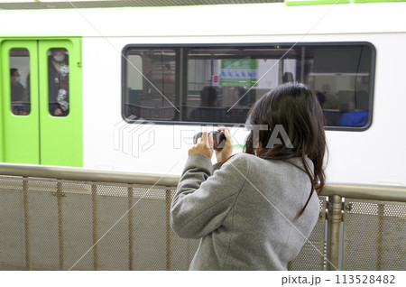 駅のプラットホームから電車を撮影する女性 駅のプラットホームから電車を撮影する女性 113528482