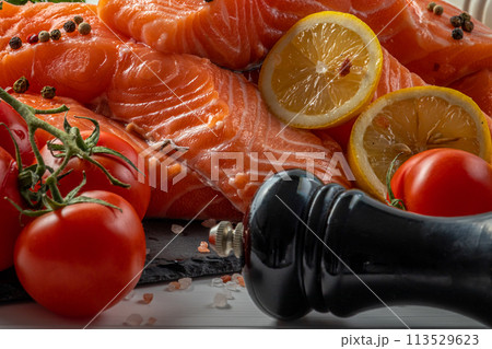 Fresh raw salmon fillet with cooking ingredients, herbs and lemon on black slate Fresh raw salmon fillet with cooking ingredients, herbs and lemon on black slate 113529623