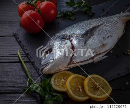 Sea bream or dorado sea fish herbs on dark slate background Top view  113529673