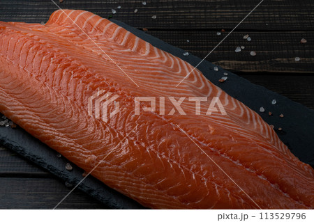 Fresh raw salmon fillet with cooking ingredients, herbs and lemon on black slate Fresh raw salmon fillet with cooking ingredients, herbs and lemon on black slate 113529796
