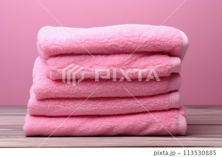 Folded pink towels on a pink background. 113530885