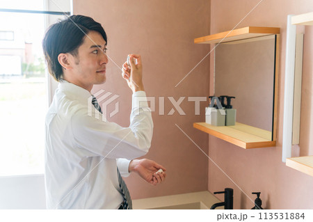 朝洗面所でスキンケア・フェイスケアするスーツ姿の男性（化粧水・身じたく・肌ケア） 113531884