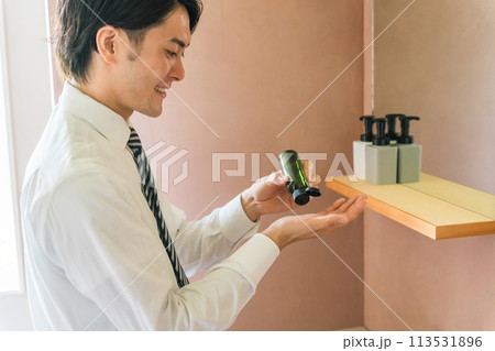 朝洗面所でスキンケア・フェイスケアするスーツ姿の男性（乳液・クリーム・保湿・身じたく・肌ケア） 113531896