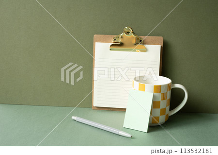Workspace notepad binder clip, pen, mug cup on green desk. khaki wall background 113532181