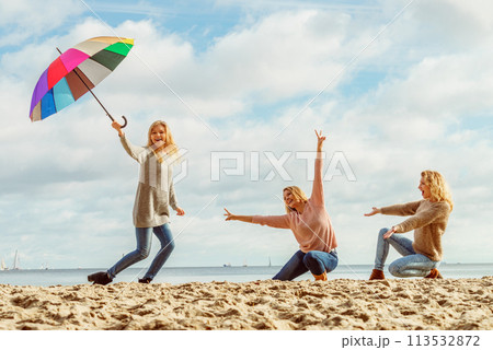 Women holding umbrella having fun with friends Women holding umbrella having fun with friends 113532872