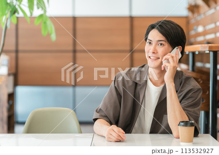 カフェ・家などでスマホを使って電話する若いアジア人男性 113532927