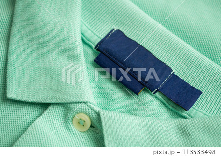 Blank blue laundry care clothes label on green shirt fabric texture background Blank blue laundry care clothes label on green shirt fabric texture background 113533498