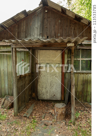 Rustic old wooden house in the woods with a small porch and a wooden door. Rustic old wooden house in the woods with a small porch and a wooden door. 113533785