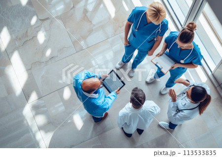 Diverse healthcare professionals using digital devices while collaborating in overhead view 113533835