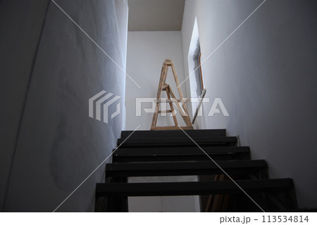 Stairs to the second floor.Construction work in a private house. Natural lighting of a flight of stairs. 113534814