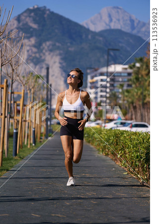 Female runner running at morning in city park. Healthy fitness woman jogging outdoors. Mountains in Female runner running at morning in city park. Healthy fitness woman jogging outdoors. Mountains in 113536923