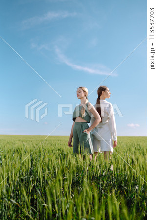 Two Beautiful woman in the green field. Nature, vacation, relax and lifestyle. Summer landscape. Two Beautiful woman in the green field. Nature, vacation, relax and lifestyle. Summer landscape. 113537703