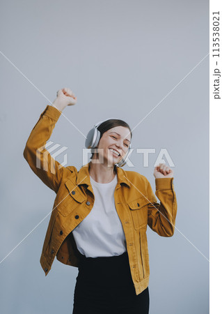 The beautiful emotional European brown-haired woman with healthy clean skin, charming smile, dressed in casual light clothes, listens and enjoys music on headphones with tablet on a white background. The beautiful emotional European brown-haired woman with healthy clean skin, charming smile, dressed in casual light clothes, listens and enjoys music on headphones with tablet on a white background. 113538021