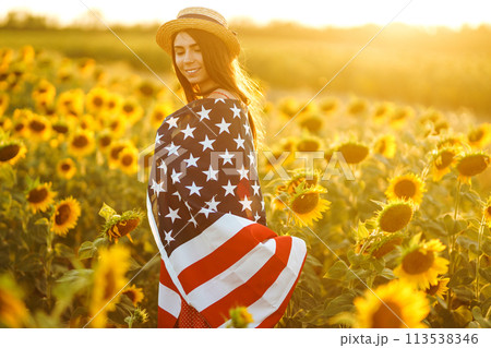 Beautiful girl in hat with the American flag in a sunflower field. 4th of July. Fourth of July. Independence Day. Beautiful girl in hat with the American flag in a sunflower field. 4th of July. Fourth of July. Independence Day. 113538346