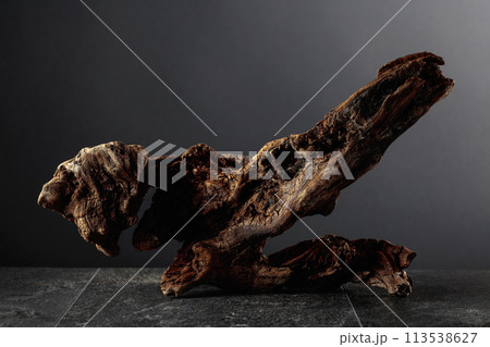 Old dry wooden snag on a black stone table. Old dry wooden snag on a black stone table. 113538627