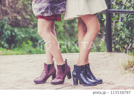 Two women presenting shoes outdoor Two women presenting shoes outdoor 113538797
